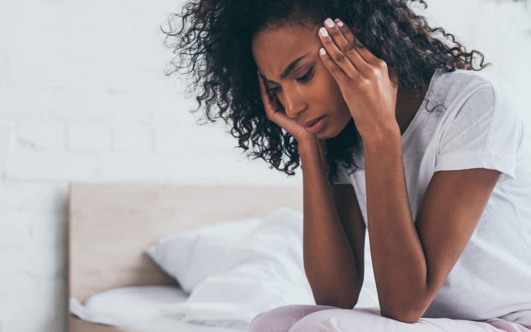 a woman sitting and holding her head as if in pain